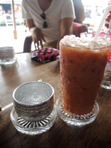 a glass of iced tea and a small cup on a table