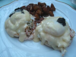 a plate of eggs benedict and some meat