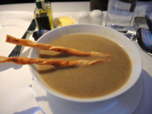 a bowl of soup with two bread sticks