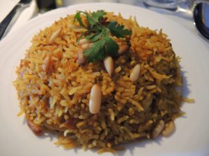 a plate of rice with nuts and parsley