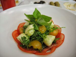 a plate of salad with tomatoes and basil