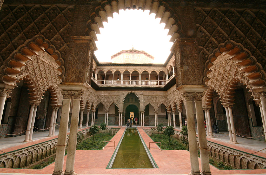 a courtyard with a pool and a building with arches and arches