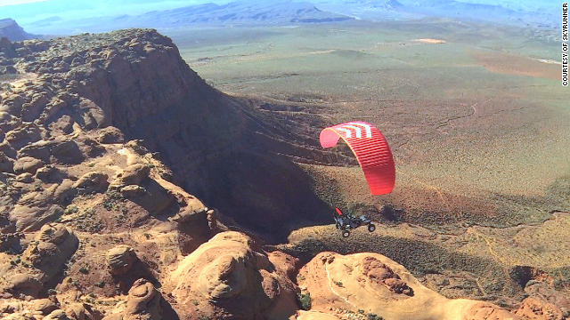 a person flying a parachute over a desert