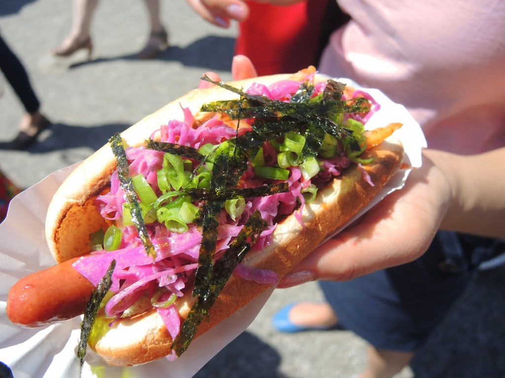 a person holding a hot dog with vegetables
