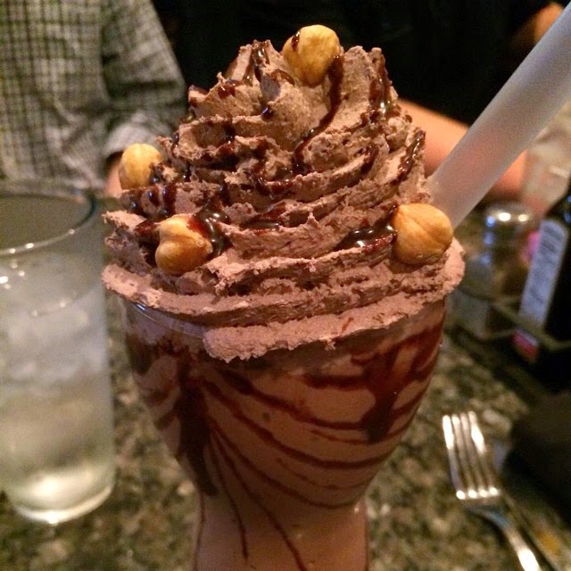a chocolate milkshake with nuts and chocolate syrup