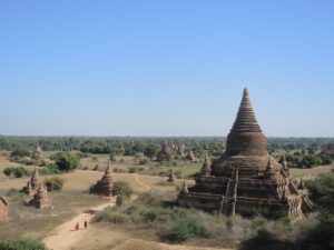 a group of buildings with a group of people walking on a dirt road