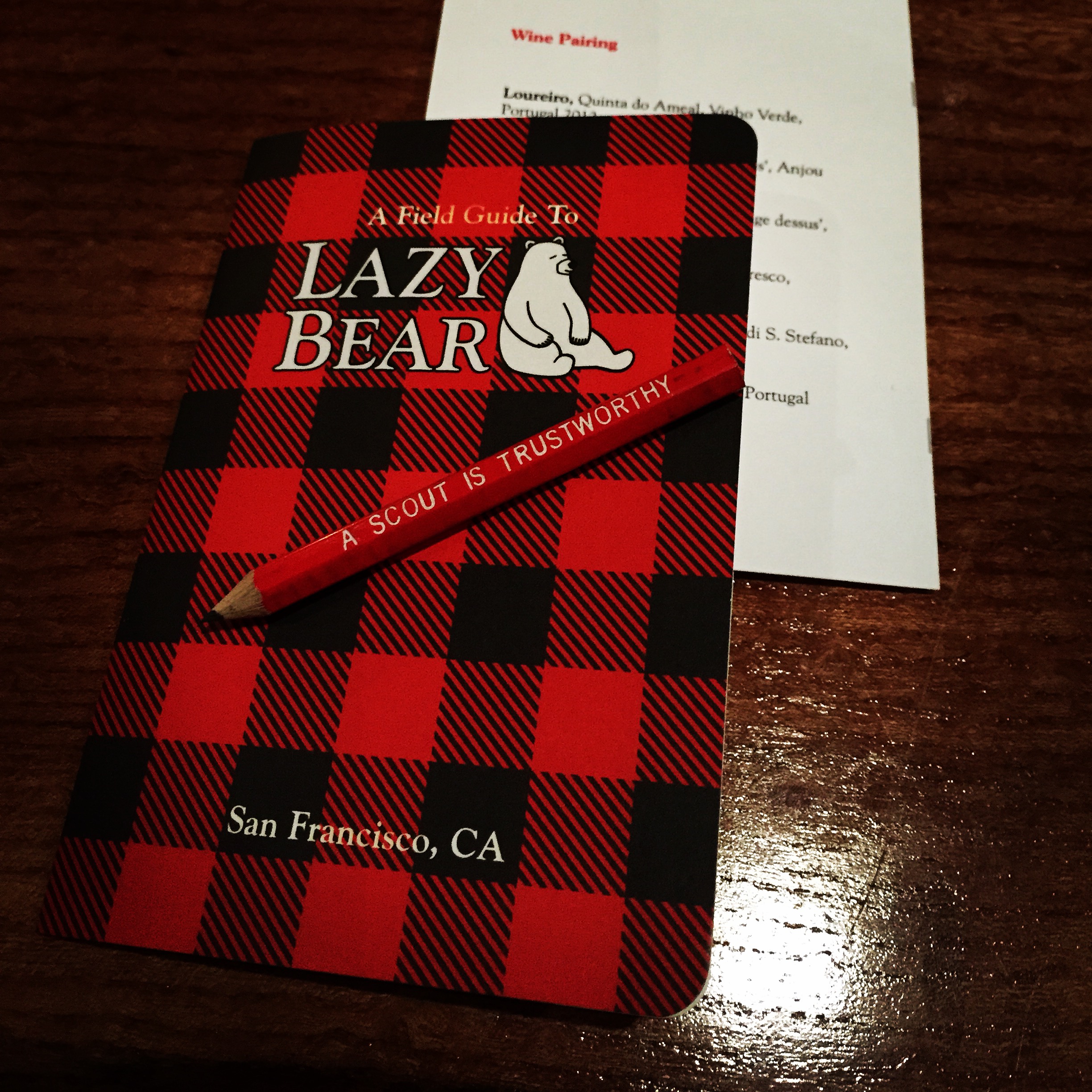 a red and black checkered book with a pencil on top of it