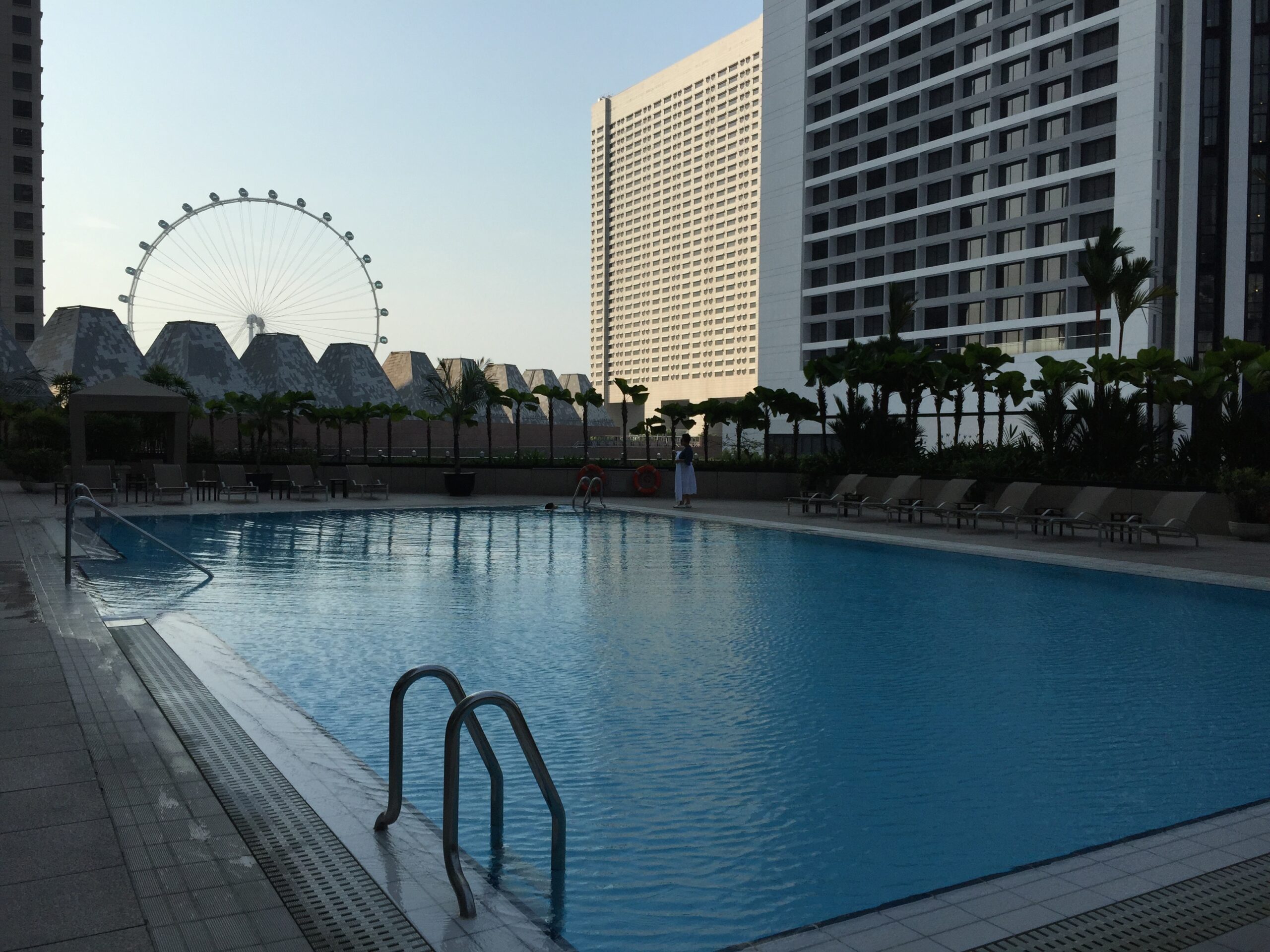 a swimming pool with a ferris wheel in the background