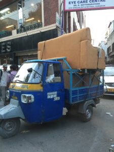 a blue and yellow truck with a couch on the back