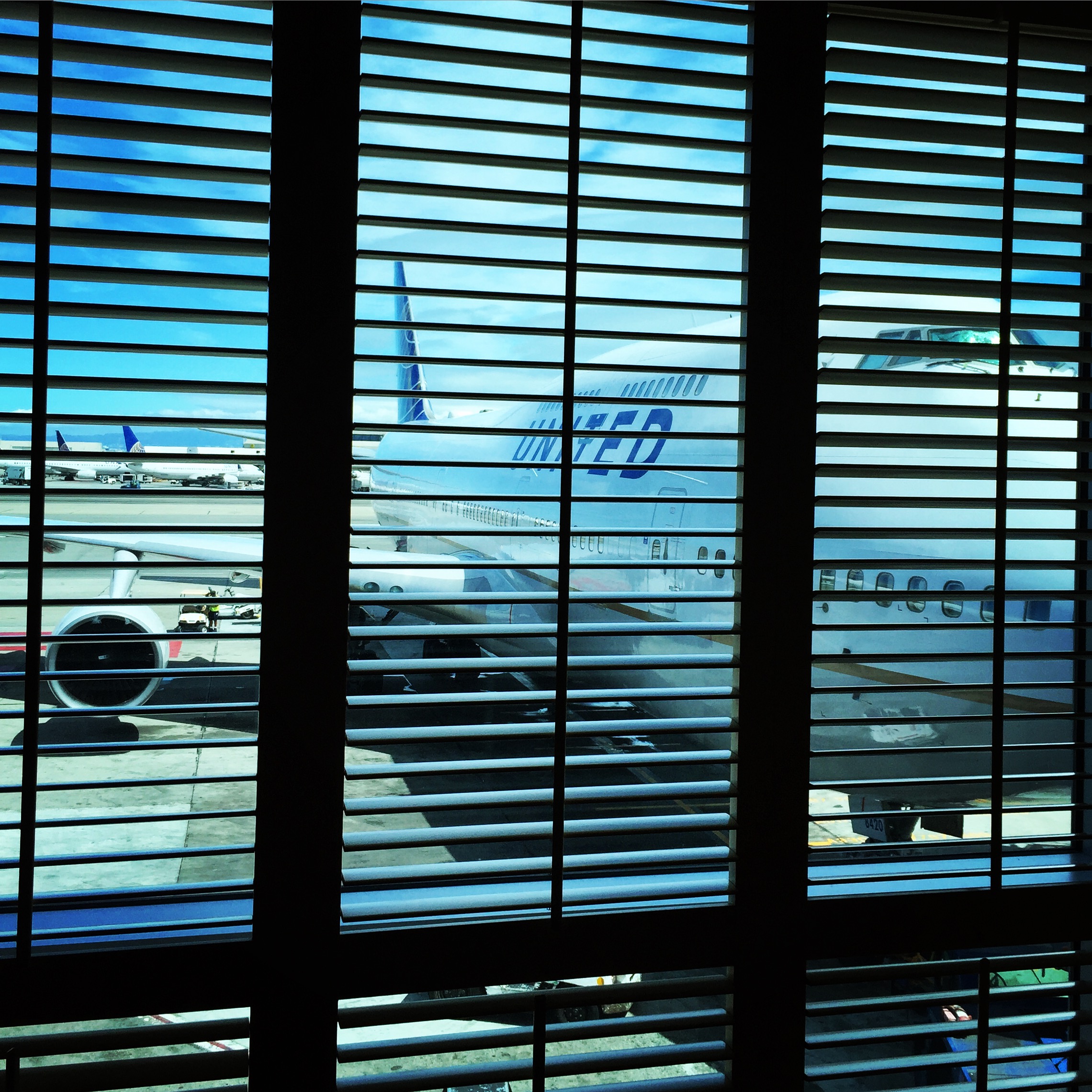 a window with blinds and a plane on the ground