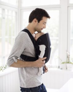 a man holding a baby in a baby carrier