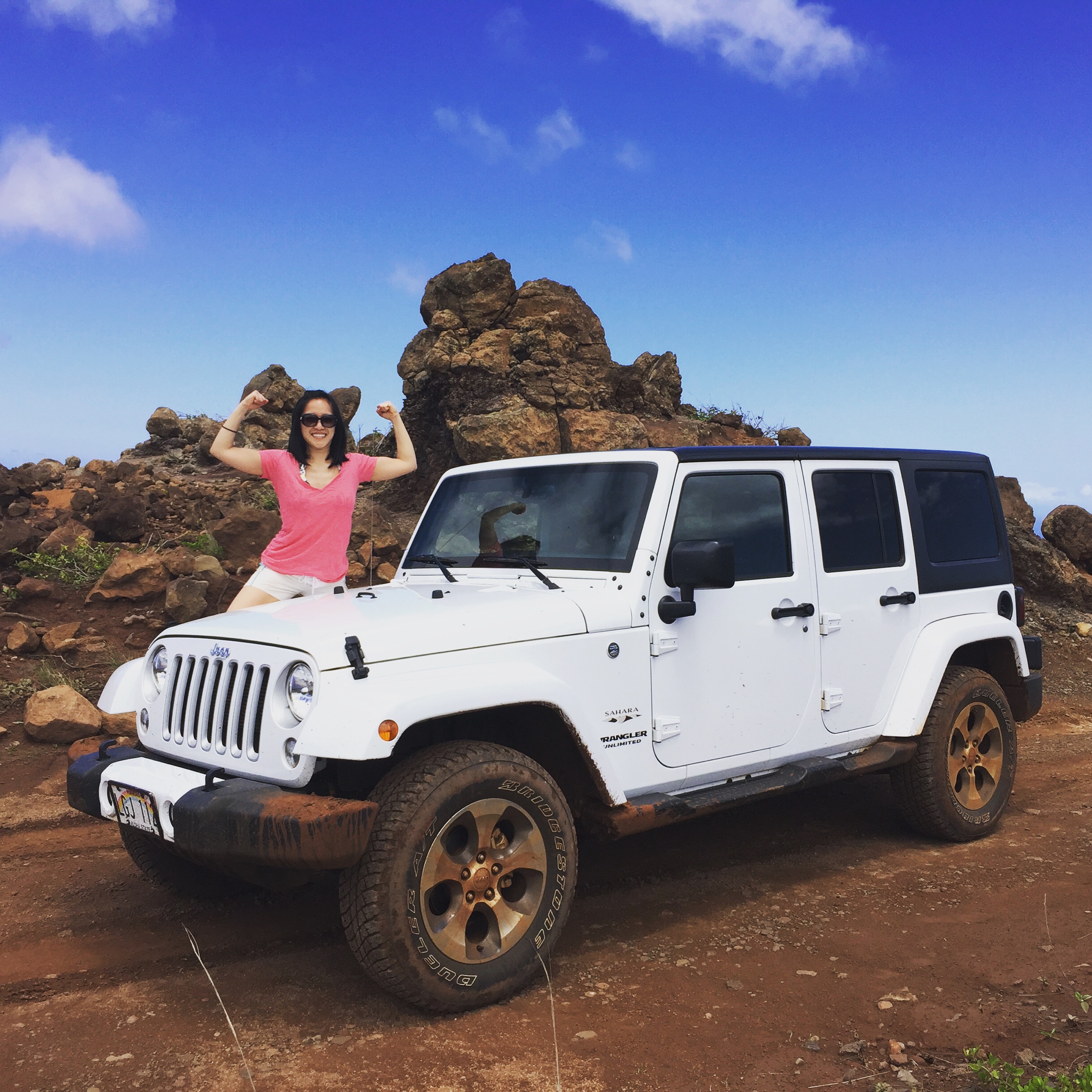 a woman standing on the hood of a white jeep