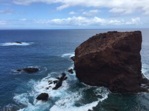 a rocky cliff with waves crashing on the water